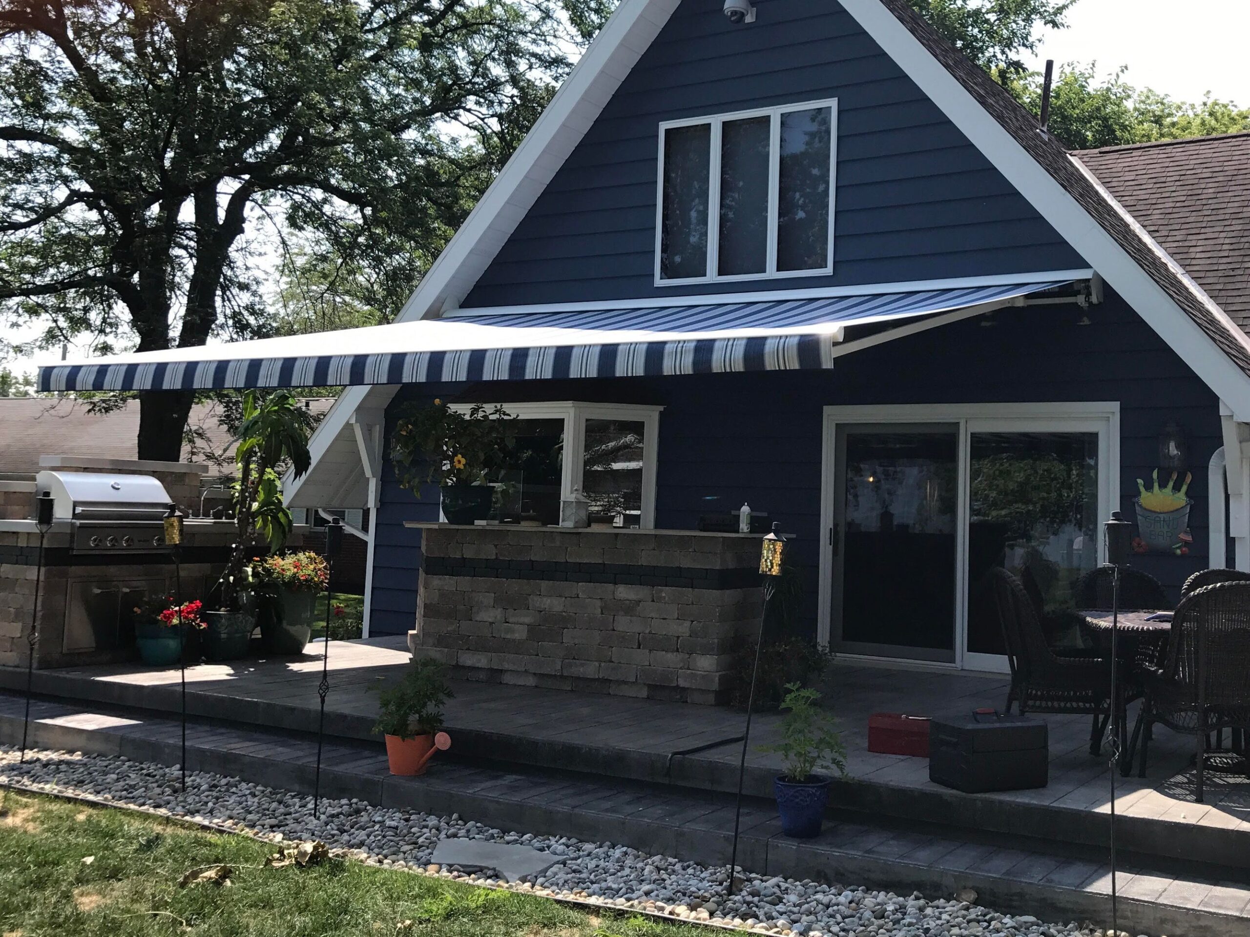 A blue house with a welcoming front porch, adorned with an awning that enhances its appeal