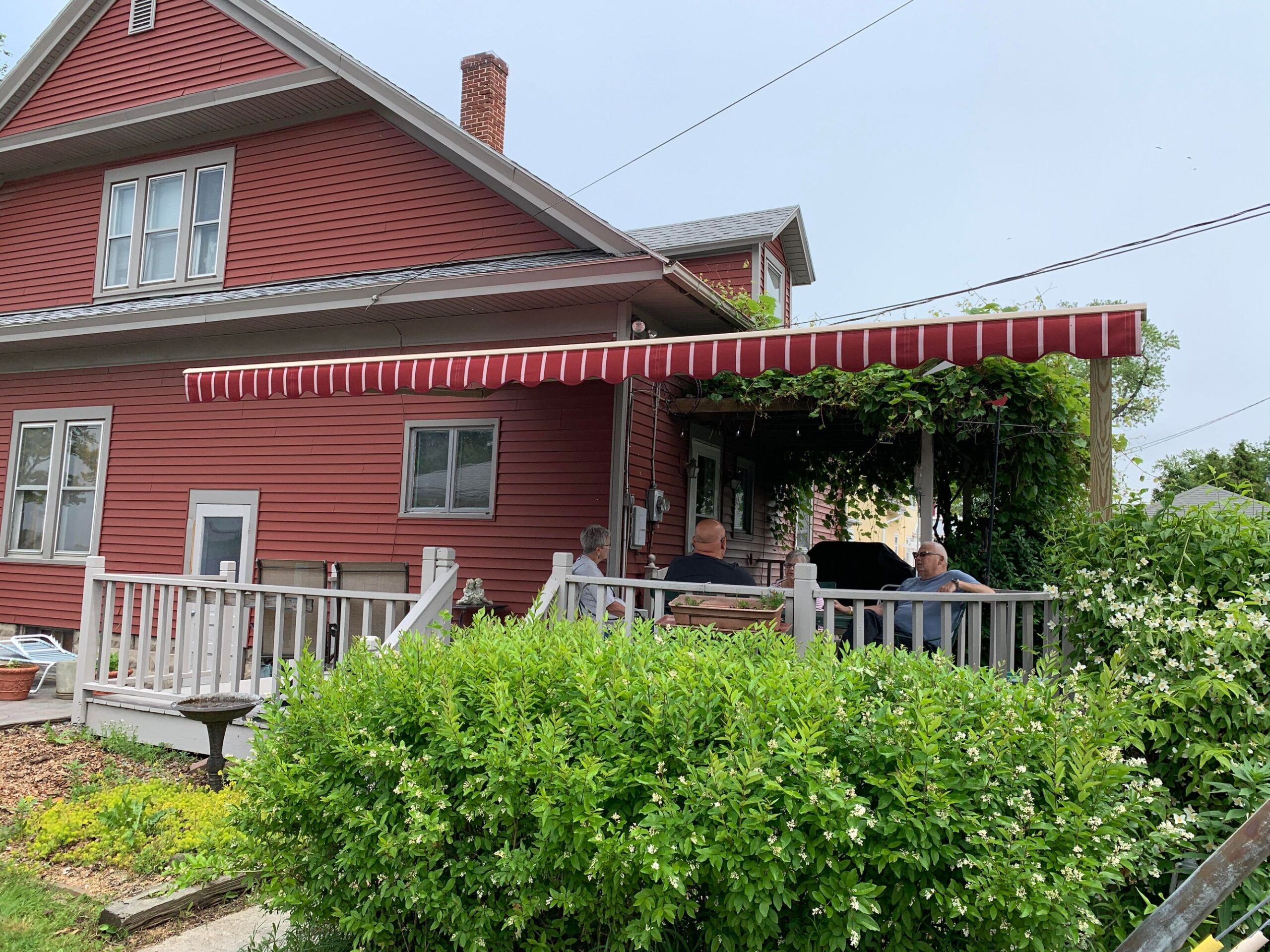 A vibrant red house featuring a matching red awning, set against a clear blue sky